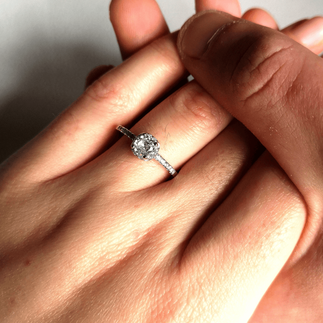 Man holding a woman's hand wearing a diamond engagement ring