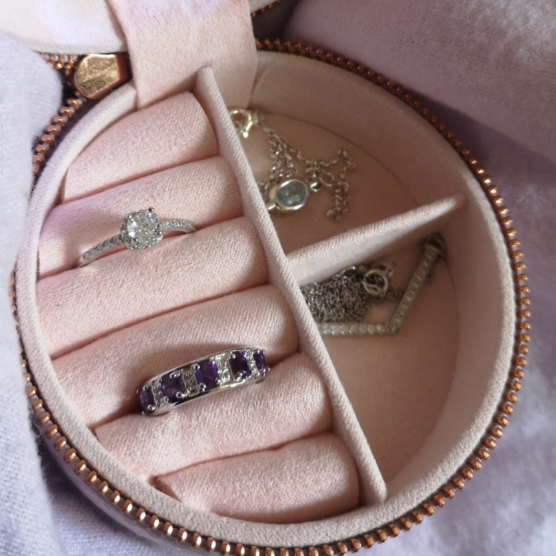 a selection of jewellery inside a round jewellery box