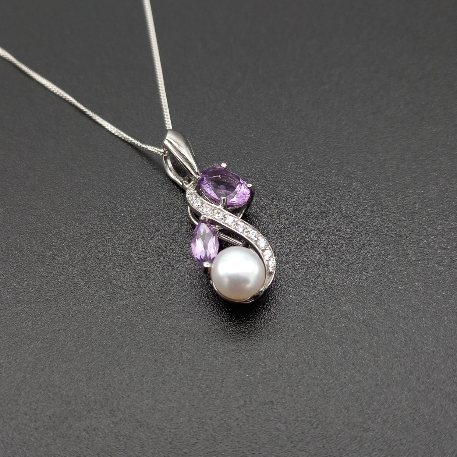 Sterling silver amethyst, pearl & cz figure of eight necklace on a black background