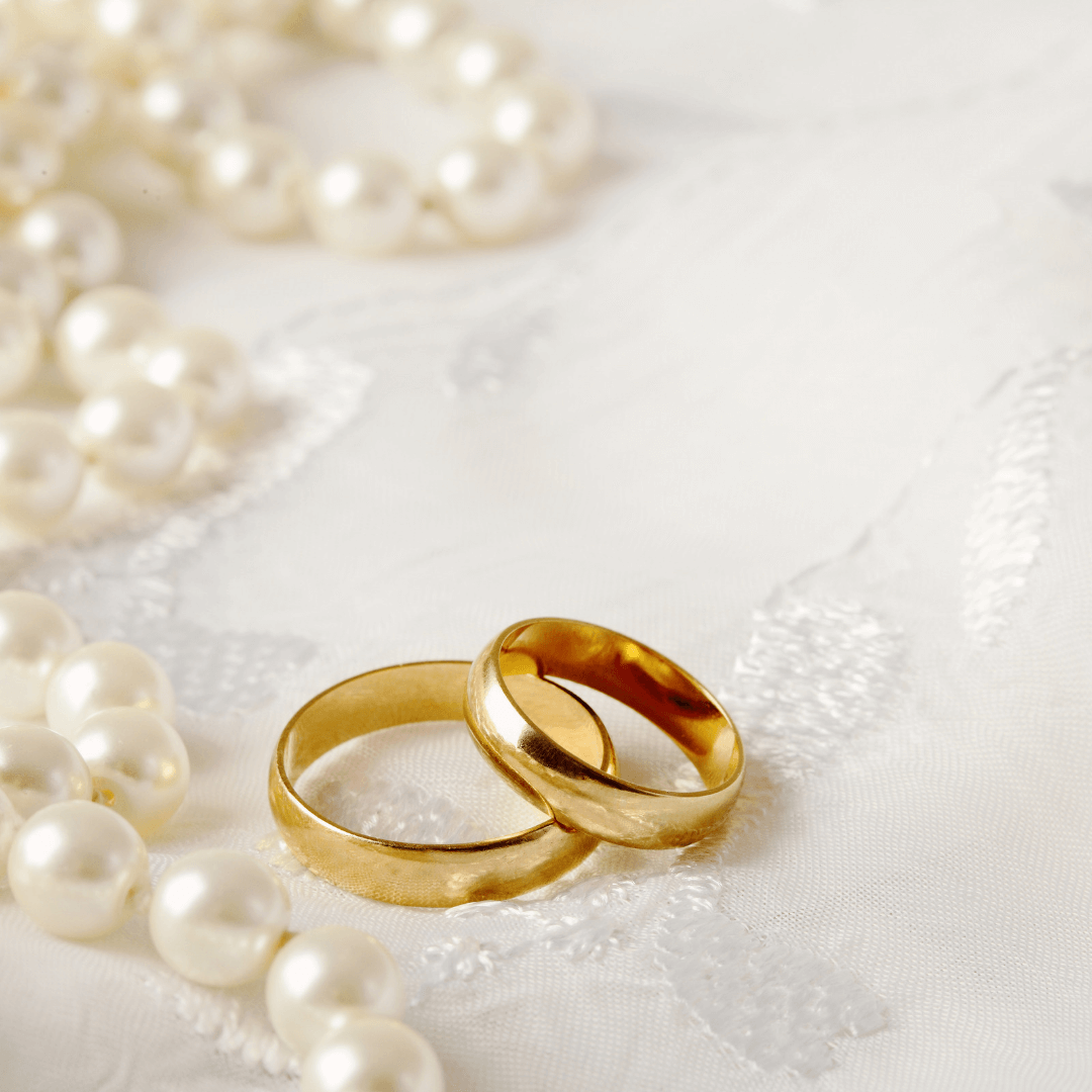 Gold wedding rings on a white background with ivory pearls